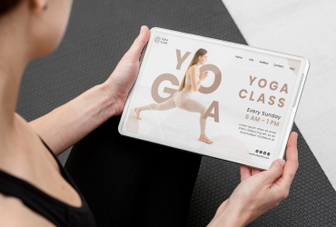 woman holding tablet with yoga website on it